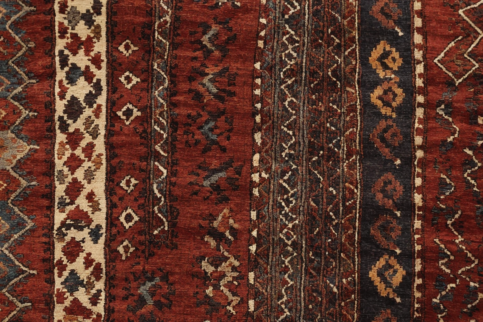 Corner detail of a hand-knotted Turkmen pile carpet showing selvedge, flat-woven kilim end and dense low pile